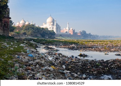 Indias contrast of ugly pollution and stunning beauty, The banks of Yamuna River polluted with garbage and beautiful Taj Mahal in the background