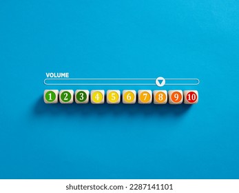 Indicator measuring volume level. High level of sound volume. Volume level numbers on wooden cubes with a volume meter on blue background.