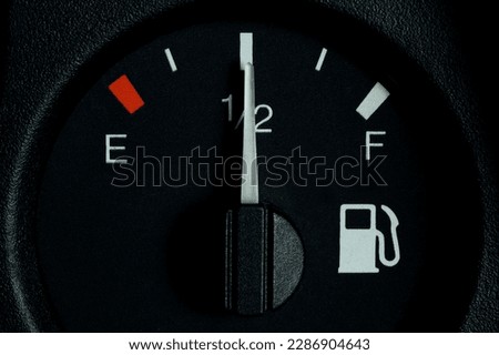 The indicator on the car panel, half of the fuel tank. Close-up. Fuel gauge indicating half.