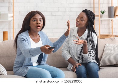 Indifference In Friendship. Young Black Woman Watching Television Not Paying Attention To Her Friend That Telling About Her Problems