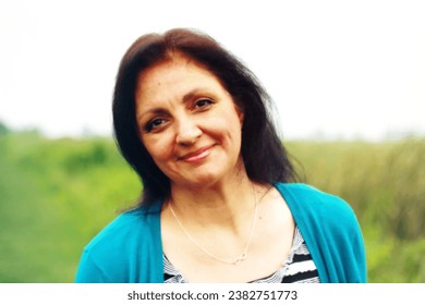 Indigenous woman. Metis. Middle aged. Mature older lady. Head and shoulders portrait. Outdoors. Dark hair. Infinity necklace Metis symbol. Visible minority. Happy. Smiling. Canadian aboriginal. 