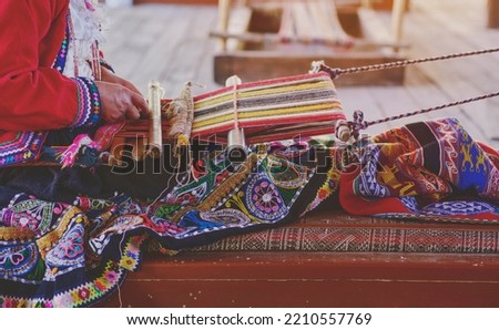 Indigenous woman showing traditional weaving technique and textile making in the Andes mountain range of South America in Peru, Selective focus.