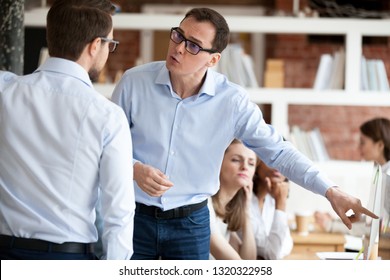 Indignant men colleagues quarrelling in shared office, having different opinion and disagreements arguing at work. Mad millennial employee accusing business partner disputing at coworking modern room