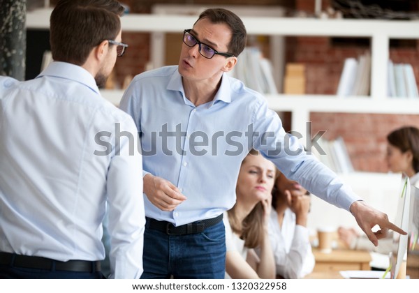 Indignant men colleagues quarrelling in shared\
office, having different opinion and disagreements arguing at work.\
Mad millennial employee accusing business partner disputing at\
coworking modern room