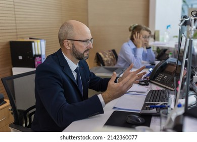 Indignant office worker sits at a desk in a modern office spaceappearing angry, annoyed and surprised.Surprised business partners at the workplace. In the center of attention is an indignant person.