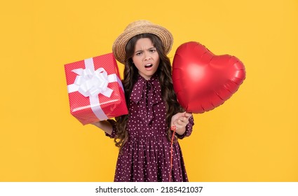 indignant teen girl with red heart balloon and present box on yellow background