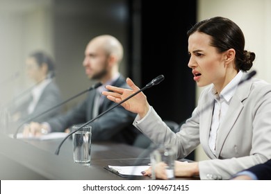 Indignant Young Female Politician Shouting Into Microphone At Conference Or Political Summit