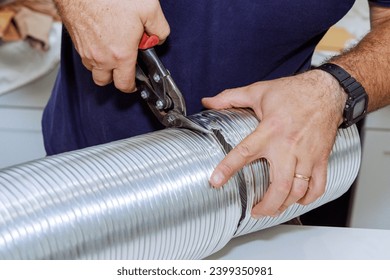 An individual cuts flexible aluminum corrugated pipe in order to connect it to ventilation system