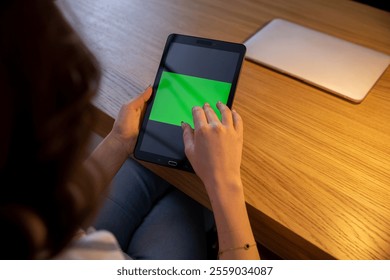 An Individual Engaged with a Tablet Featuring a Green Screen User Interface Display - Powered by Shutterstock