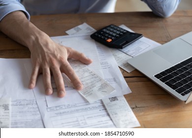 Individual Entrepreneur Make Analysis Of Firm Expenses, Accountant Do Paperwork Concept. On Desk Lot Of Receipts, Calculator And Laptop Close Up View. Man Sit At Table Reviewing Bills, Managing Budget