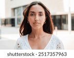 Individual portrait of a Hispanic girl with a serious expression looking at camera. Young teenage woman staring front with a neutral demeanor. Only one Latin female gazing with a composed attitude