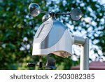 Individual weather station with a black wind vane is mounted on a pole in a garden. Personal meteorology and weather forecasting