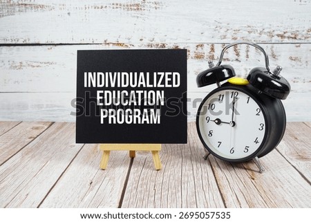 Individualized Education Program text with easel and alarm clock on wooden background