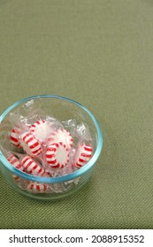 Individually Wrapped With Clear Plastic White And Red Peppermint Hard Candy Discs In A Glass Bowl On A Green Tablecloth. White And Red Peppermint Hard Candy In A Clear Bowl On A Green Tablecloth.