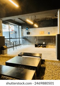 Indonesia, 2 de junio de 2024: Bagi Kopi Café cerca de la estación Bogor ofrece un ambiente elegante y moderno ideal para la generación Z, con bancos negros, lámparas largas y tonos grises y negros frescos. Foto de contenido editorial de stock