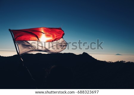 Indonesia flag flying on the sunrise  background in top of mountain. Independence day Indonesia concept.