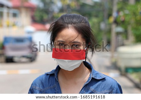 Indonesia flag on hygienic mask. Masked Asian woman prevent germs and wear denim skirt dress. concept of Tiny Particle protection or virus corona or Covid 19.