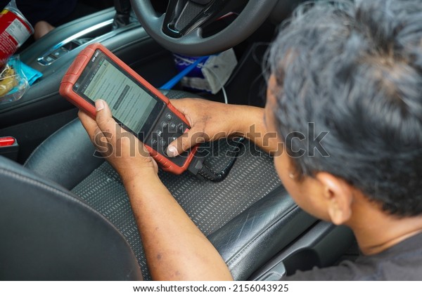Indonesia, Jakarta, may 12, 2022 : Car mechanic\
repair service and car engine checking by car diagnostic tool\
scanner or computer Diagnostics Software. Expert mechanic working\
in auto repair\
workshop.
