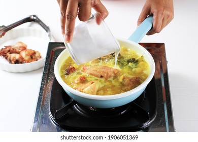 Indonesia Thai Home Cooking Process, Female Hand Pour Coconut Milk In To The Pan, Making Indonesian Thai Yellow Style Curry, Traditional Asian Gourmet Called Opor Ayam, Gulai, Kari, Or Kare