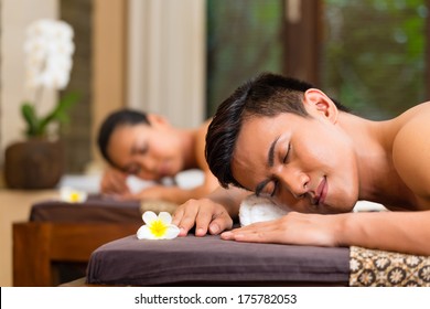 Indonesian Asian Couple Man And Woman In Wellness Beauty Spa Having Aroma Therapy Massage With Essential Oil, Looking Relaxed