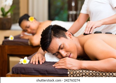 Indonesian Asian Couple Man And Woman In Wellness Beauty Spa Having Aroma Therapy Massage With Essential Oil, Looking Relaxed