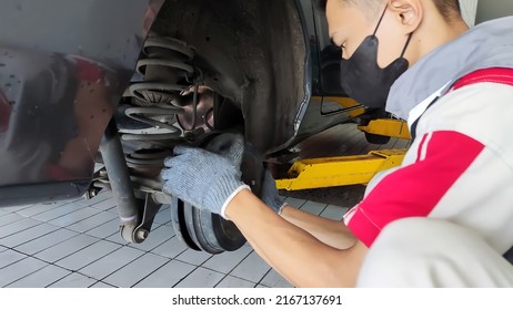 An Indonesian car mechanic is checking Rear brake of a car in an authorized workshop dealer