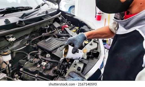 An Indonesian car mechanic is pouring engine flush liquid to a gasoline engine car in an authorized workshop dealership - Shutterstock ID 2167140593