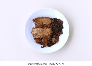 Indonesian Chinese traditional food named "babi hong" i.e. braised pork belly cooked with salted vegetable, shiitake mushroom and soysauce, served on plate isolated on white background, top view