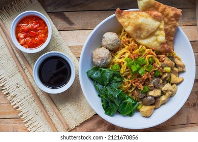 Indonesian famous street food Mie Ayam or chicken noodles served with meatballs, vegetables , fried wonton and sambal