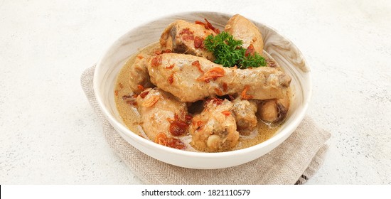 Indonesian Food : Opor Ayam or Chicken Curry. Chicken cooked in coconut milk and spices. It is served to celebrate Eid Al Adha and Eid Al Fitr. Isolated and copy space on white background.