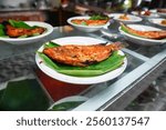 Indonesian food, Padang cuisine buffet: Fish in coconut milk, fried fish, grilled fish, beef and other dishes are displayed in a glass display case.