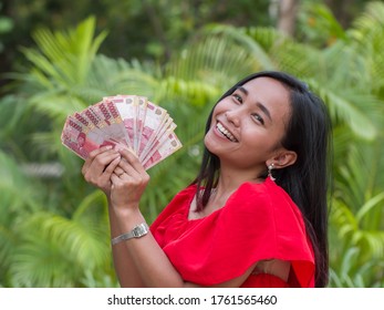 Indonesian money in the hands of an asian girl.
