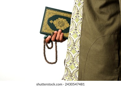 An Indonesian Muslim man holding the Holy Quran and tasbih on a white background prepares to perform Itikaf at a mosque during the last ten days of Ramadan, seeking spiritual reflection and renewal