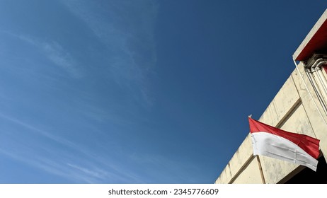 The Indonesian national flag was raised beside the old building under a clear sky.  - Shutterstock ID 2345776609