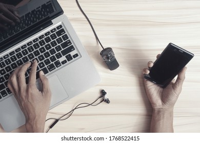 Indonesian person hand working on home office workplace with laptop, smartphone, External Webcam, and Head set. A concept of new normal work from home with connection and internet technology