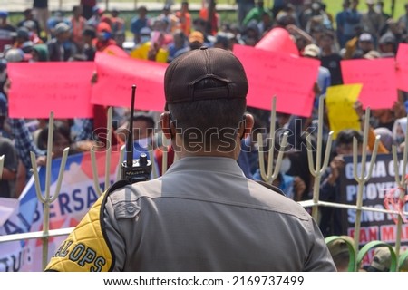 An Indonesian policeman was standing watching the movements of the demonstrators. Tegal, Central Java, Indonesia. 20 June 2022.