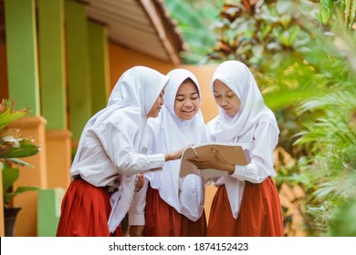 Indonesian school student reading a book together in school garden - Shutterstock ID 1874152423