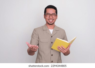 Indonesian school teacher smiling happy while holding a book - Powered by Shutterstock