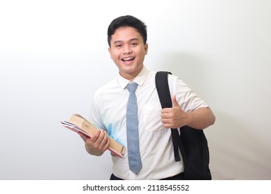 Indonesian Senior High School Student Wearing White Shirt Uniform With Gray Tie Showing Good Job Hand Gesture, Thumb Up Finger. Isolated Image On White Background