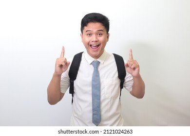 Indonesian Senior High School Student Wearing White Shirt Uniform With Gray Tie Showing Product, Pointing Up At Something And Smiling. Advertising Concept. Isolated Image On White Background