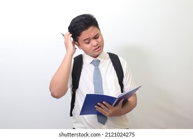 Indonesian Senior High School Student Wearing White Shirt Uniform With Gray Tie Writing On Note Book Using Pen And Thinking About An Idea. Isolated Image On White Background