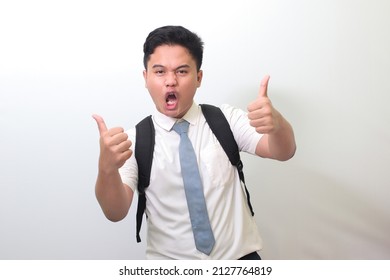 Indonesian Senior High School Student Wearing White Shirt Uniform With Gray Tie Smiling And Looking At Camera, Making Thumbs Up Hand Gesture. Isolated Image On White Background