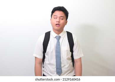 Indonesian Senior High School Student Wearing White Shirt Uniform With Gray Tie Yawning With Closed Eyes Due To Overworking. Isolated Image On White Background