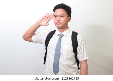 Indonesian Senior High School Student Wearing White Shirt Uniform With Gray Tie Giving Salute Pose With Hand During Flag Ceremony. Isolated Image On White Background