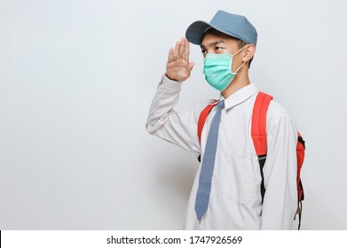 Indonesian Senior Student Of Senior High School In Indonesian Wearing Protection Face Mask With School Uniform Giving Salute, Isolated On Gray Background