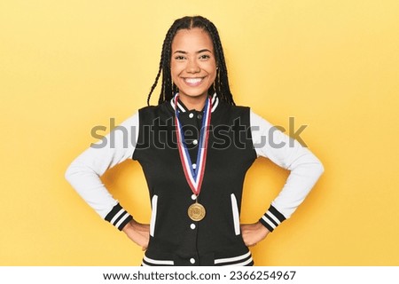 Indonesian student girl showcasing her medal on yellow studio backdrop