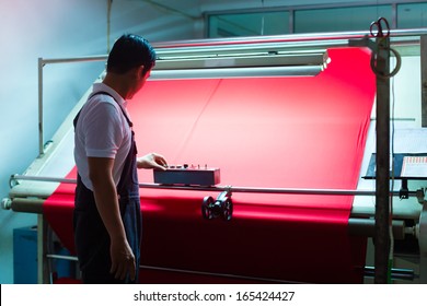 Indonesian Textile Worker In A Manufacturing Plant Controls The Quality Of A Fabric Roll And Logs Any Faults