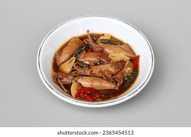 Indonesian traditional food named "cumi masak tauco" i.e. squid cooked with tauco, soy sauce and spices served on plate isolated on gray background - Shutterstock ID 2365454513