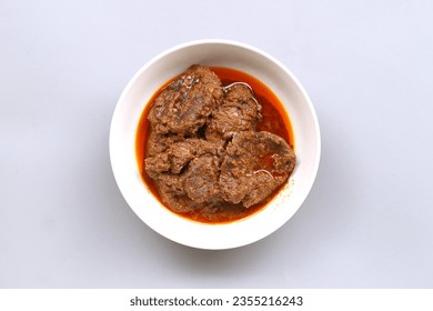 Indonesian traditional food named "rendang sengkel" i.e. beef shank slow cooked and braised with santan or coconut milk and spices served on bowl isolated on white background, top view