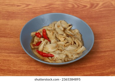 Indonesian traditional food named "tumis jamur tiram putih" i.e. sauteed slices of mushroom, served on plate in wooden table, top view - Shutterstock ID 2365384895
